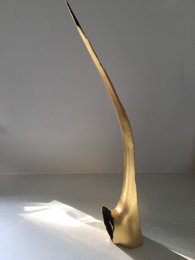 photographs of a gold and black sculpture that looks like a wing on a grey and white background